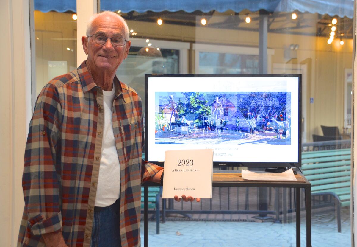 Lawrence Sherwin exhibits his slideshow images while holding his book of selected photos.