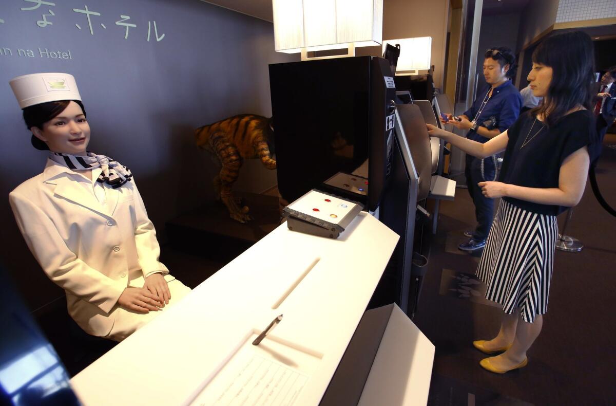 A receptionist robot, left, greets a hotel employee, right, demonstrating how to check in for the media at the new hotel, aptly called Henn na Hotel or Weird Hotel, in Sasebo, southwestern Japan, Wednesday, July 15, 2015. From the receptionist that does the check-in and check-out to the porter that's a stand-on-wheels taking luggage up to the room, the hotel, that is run as part of Huis Ten Bosch amusement park, is "manned" almost totally by robots to save labor costs. (AP Photo/Shizuo Kambayashi)