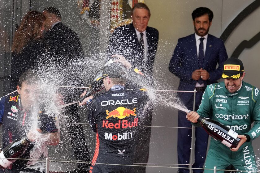 First place, Red Bull driver Max Verstappen of the Netherlands, center, celebrates on the podium with second place, Aston Martin driver Fernando Alonso of Spain, right, at the finish of the Monaco Formula One Grand Prix, at the Monaco racetrack, in Monaco, Sunday, May 28, 2023. (AP Photo/Luca Bruno)