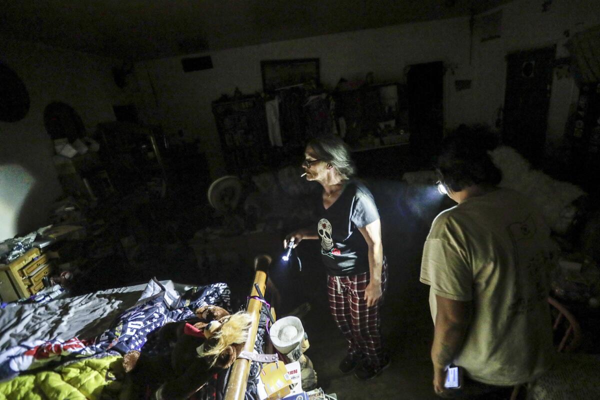 Chavela Padilla, right, an emergency response team member, walks with Trona resident Ronnie Tolbert as she sorts through debris in her home.
