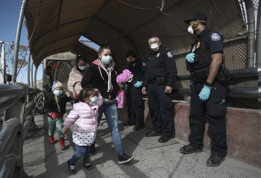 A migrant family wearing face masks crosses the border into El Paso, Texas.