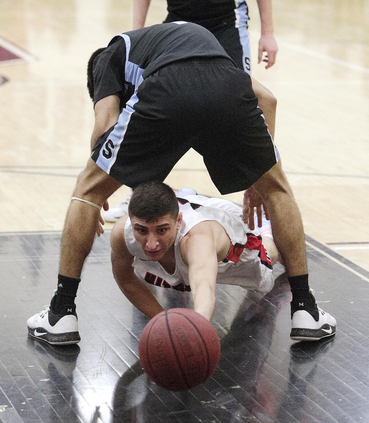 Glendale's Manny Kapoushian dives through the legs of Salesian's Efren Lemus for a loose ball in the CIF Southern Section division III-AAA second-round boys' basketball playoff in at Glendale High School on Friday, February 14, 2020. Salesian won the game in overtime beating Glendale 55-49.
