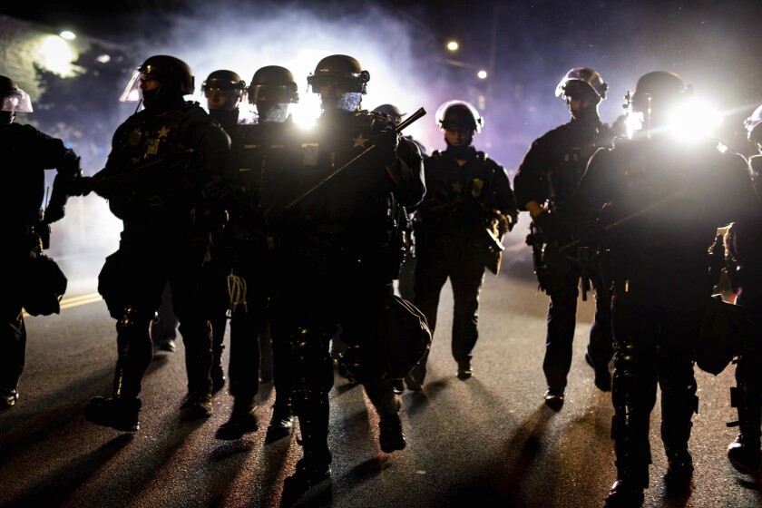 In this Aug. 9, 2020 photo, Portland, Ore., police officers in riot gear advance on a group of protesters after a demonstration was declared an "unlawful assembly." Despite passage of a 2020 Oregon law tracking decertified officers statewide, most complaints of misconduct remain closed. (Maranie Rae Staab via AP)