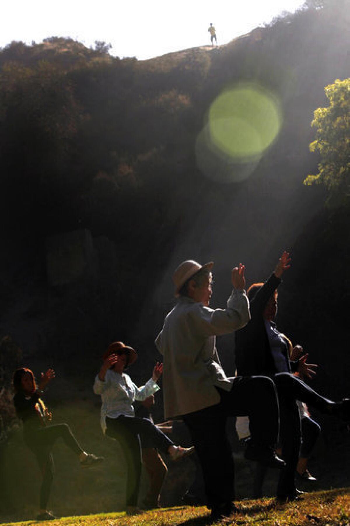 Kiki Kiko, center in hat, of Studio City, joins others to practice tai chi in Griffith Park's Bronson Canyon Park.