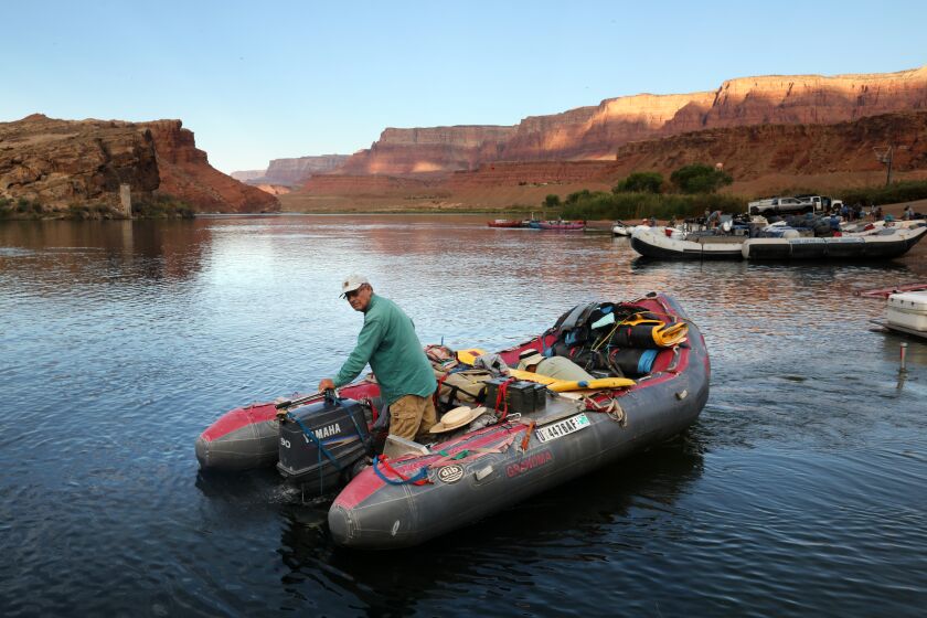 Lake Powell-June 29, 2022-John Weisheit, age 68, puts at Lees Ferry to heard towards Glen Canyon Dam, while , other rafters start their journey down river through the Grand Canyon. Weisheit has been working to conserve the Colorado River for over 20 years. He visits Lake Powell where water levels are down drastically due to drought, overuse, and mismanagement. Weisheit worked as a Colorado River guide for 21 years. He is now conservation director of Living Rivers, a conservation organization he co-founded, which works to restore and protect the Colorado River for future generations. (Carolyn Cole / Los Angeles Times)