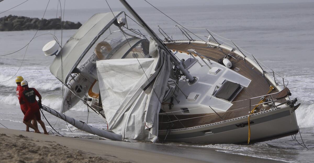 Los Angeles County lifeguards work to secure a sailboat that ran aground on Venice Beach.
