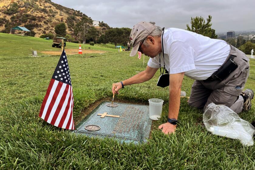 Los Angeles, California-Former Judge Lance Ito attends to the grave of his wife Margaret "Peggy" York, at Forest Lawn memorial park. "Peggy" died on October 17, 2021, at 80, after an illness. Ito brushes on bronze tablet oil to make it shine. (Steve Lopez / Los Angeles Times)