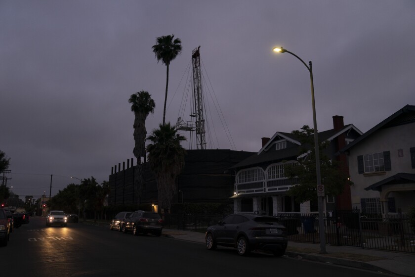 A vehicle drives past the Jefferson oil drill site located in the residential area in Los Angeles, Wednesday, June 2, 2021. University of Southern California researchers found people living near wells in Jefferson Park reported significantly higher rates of wheezing, eye and nose irritation, sore throat and dizziness than neighbors living farther away. The researchers likened the respiratory harm caused by living near the oil fields to daily exposure to secondhand smoke or exhaust from a busy highway. (AP Photo/Jae C. Hong)