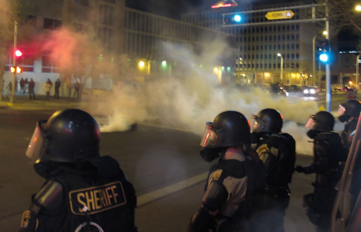 Riot police launch tear gas toward activists in downtown Albuquerque following a Sunday protest around the city over a series of deadly police shootings.