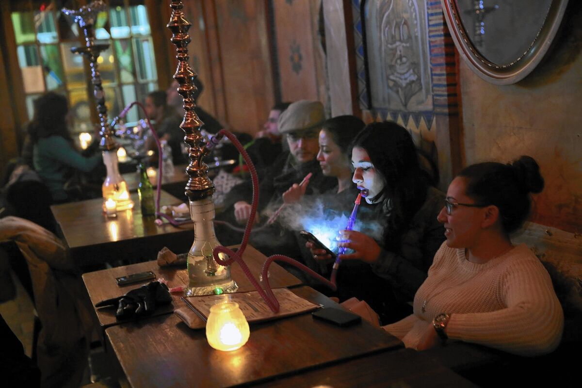 Nashwa Yosry, 20, looks at her cellphone as she smokes a hookah pipe at Sahara East in New York. It's one of 13 hookah bars targeted for closure after health inspectors found tobacco in the pipes.
