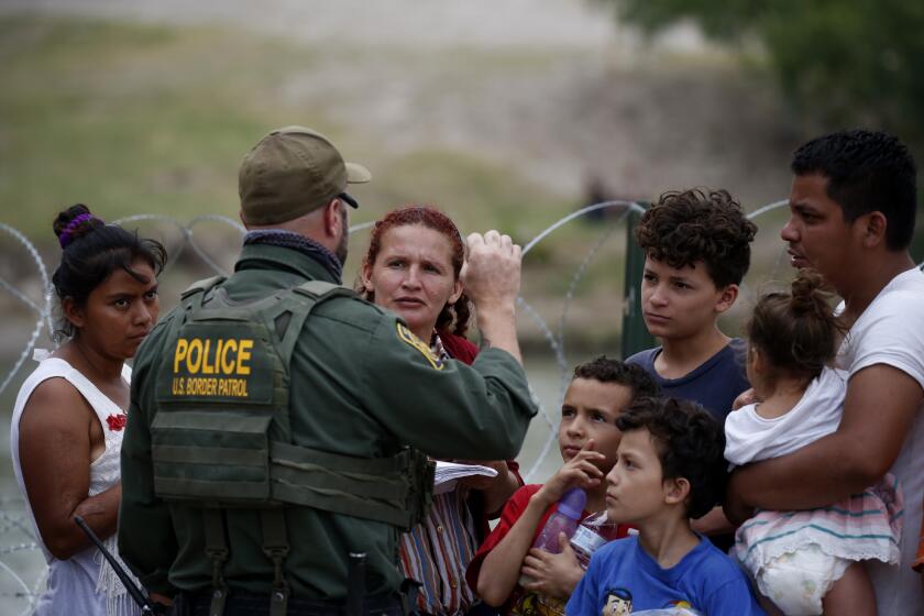 A Border Patrol officer talks to migrants after they crossed the Rio Grande river in Eagle Pass, Texas, Sunday May 22, 2022. The U.S. government has expelled migrants more than 1.9 million times under Title 42, named for a 1944 public health law, denying them a chance to seek asylum as permitted under U.S. law and international treaty for purposes of preventing the spread of COVID-19. President Joe Biden wanted to end Title 42, but a federal judge in Louisiana issued a nationwide injunction that keeps it intact. (AP Photo/Dario Lopez-Mills)