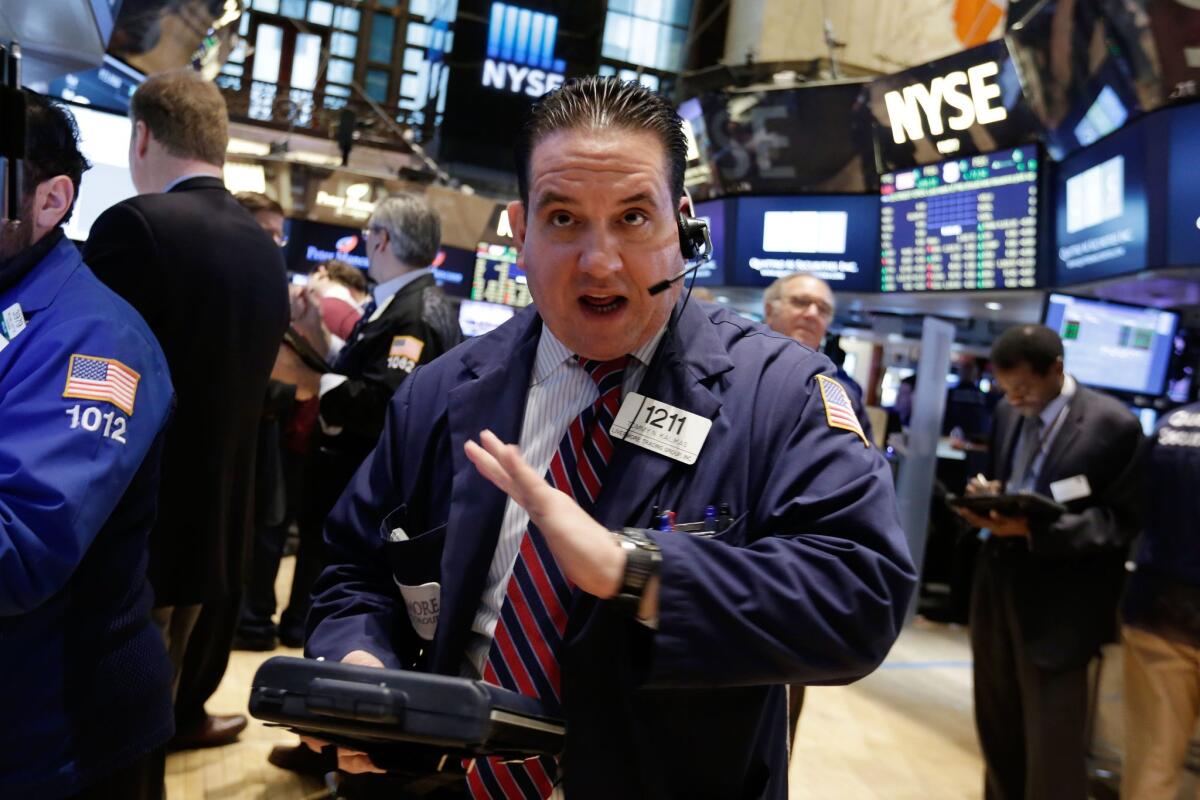 Trader Tommy Kalikas talks on his mobile phone as he works on the floor of the New York Stock Exchange Monday. U.S. stocks fell on lower oil prices and disappointing home sales data.