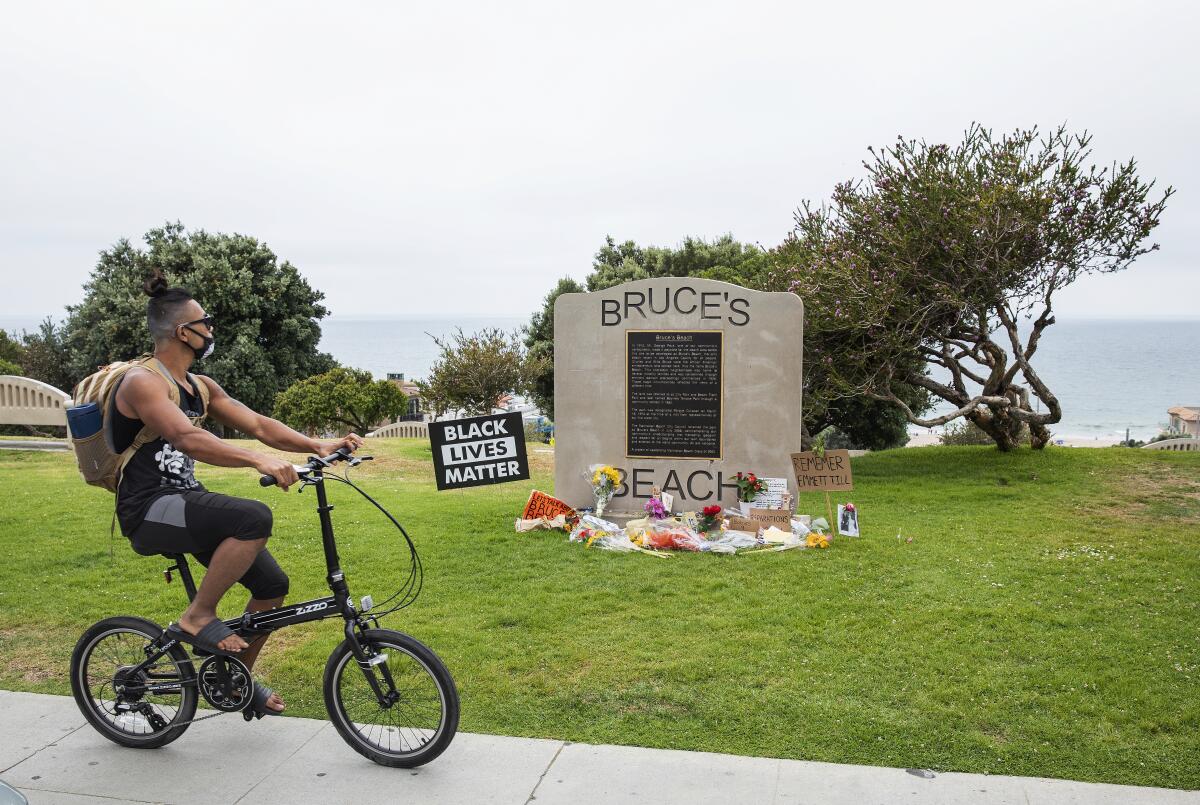 A male bike rider pauses at a plaque that stands at Bruce's Beach in Manhattan Beach.