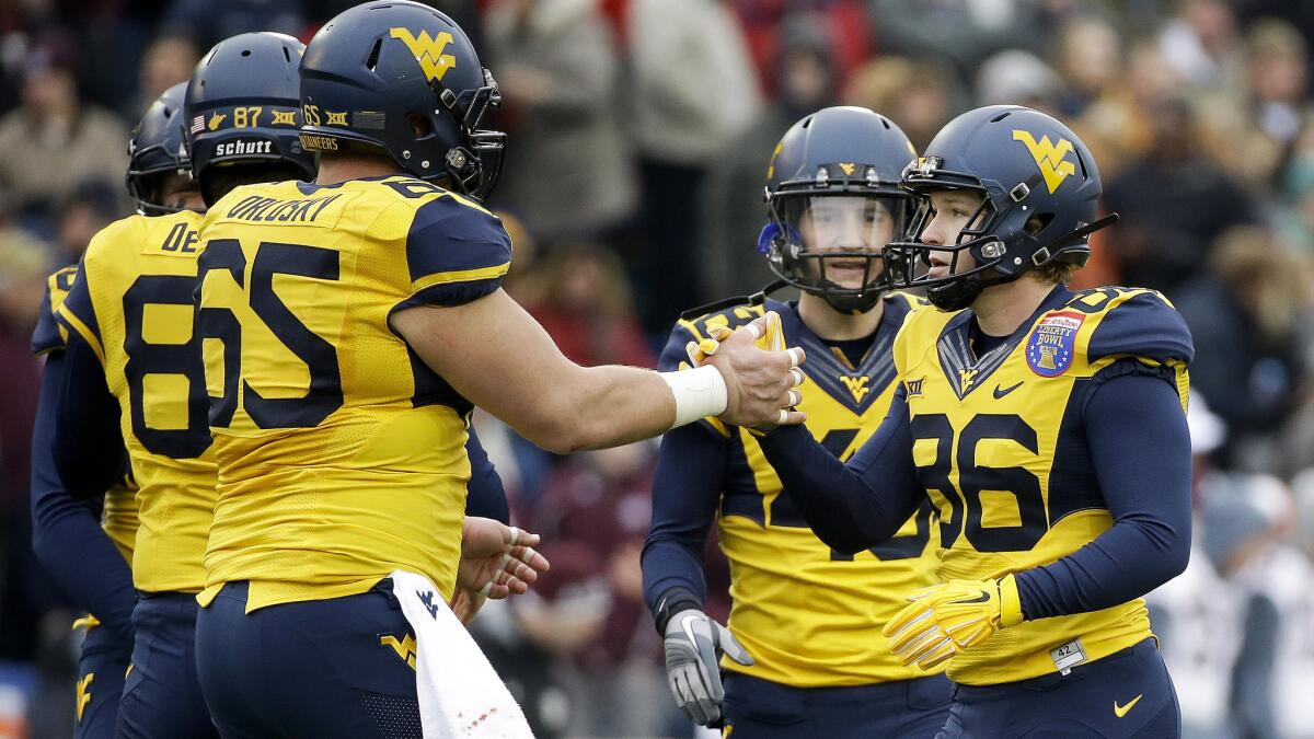 West Virginia place kicker Josh Lambert is congratulated by his teammates after kicking a field goal against Texas A&M in the Liberty Bowl on Dec. 29. West Virginia was placed under probation by the NCAA on Wednesday.