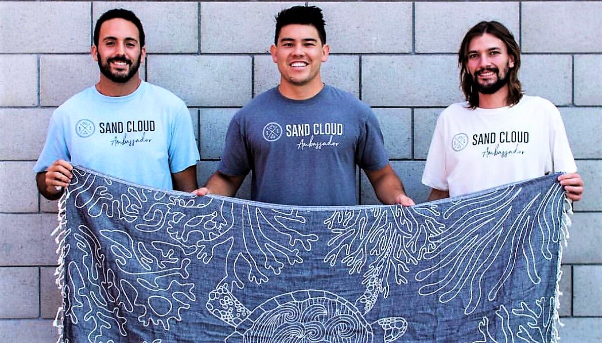 The co-founders of Sand Cloud, from left, Brandon Leibel, Steven Ford and Bruno Aschidamini, display one of the lightweight, sand-resistant beach towels that their company manufactures.
