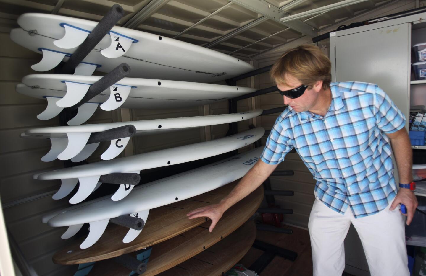Assistant Professor of Kinesiology Sean Newcomer shows surfboards that were specifically designed to vary in shape and volume so that they can be used for paddle testing in a swim flume.