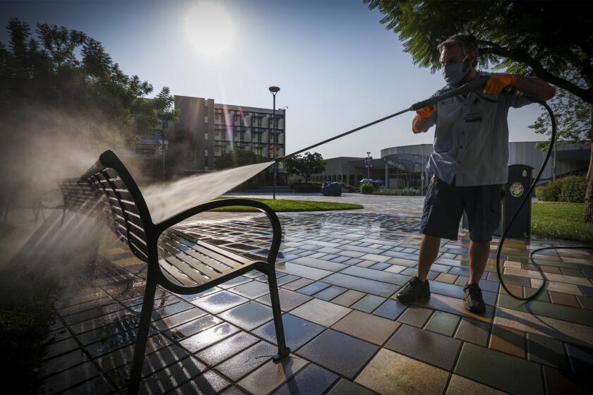 FULLERTON, CA - AUGUST 21: Brett Nickman power washes benches in preparation of reopening for Fall Semester 2020 at Cal State University of Fullerton on Friday, Aug. 21, 2020 in Fullerton, CA. (Irfan Khan / Los Angeles Times)