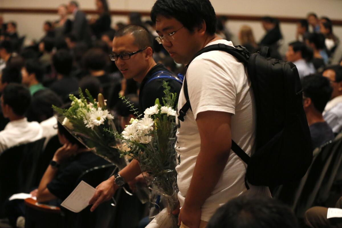 Students bring white flowers to the memorial service to honor Xinran Ji.