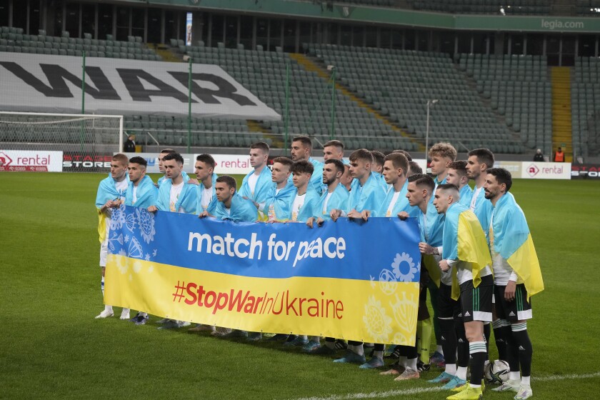 Jugadores posan con una pancarta en apoyo a Ucrania antes de un partido amistoso de caridad 