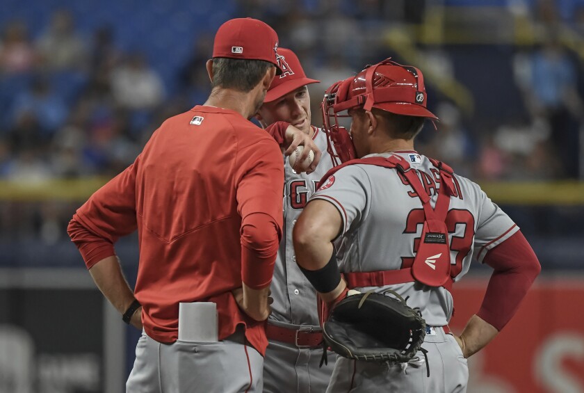 Angels pitching coach Matt Wise, left, talks with starter Griffin Canning, center, and catcher Max Stassi.