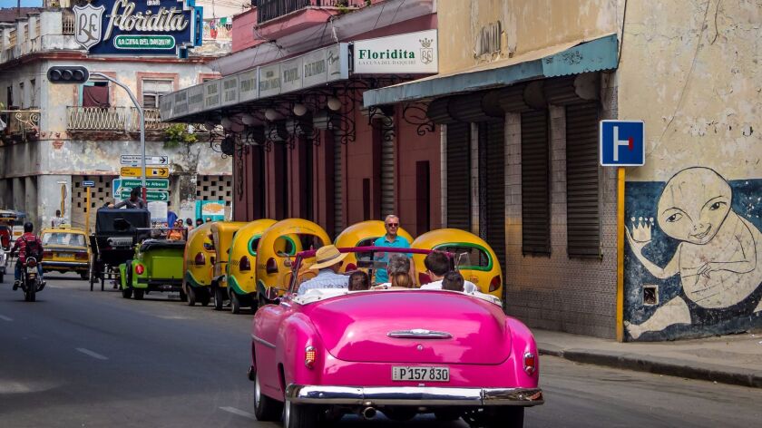 A vintage car is driven toward Floridita restaurant in Old Havana, Cuba.