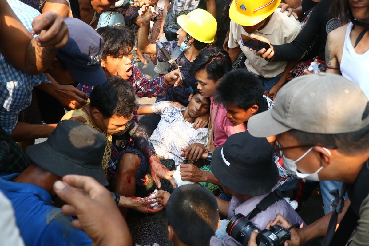 FILE - Anti-coup protesters surround an injured man in Hlaing Thar Yar township in Yangon, Myanmar Sunday, March 14, 2021. The killing of at least 65 protesters in Myanmar’s biggest city on March 14 this year was planned and premeditated, and the perpetrators must be brought to justice, a rights watchdog said in a report released Thursday, Dec. 2, 2021. (AP Photo/File)