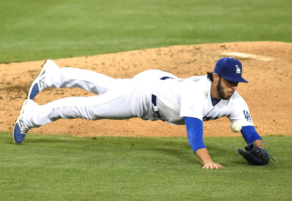 Dodgers starter Mike Bolsinger makes a diving stop of a ground ball from San Diego's Will Venable.