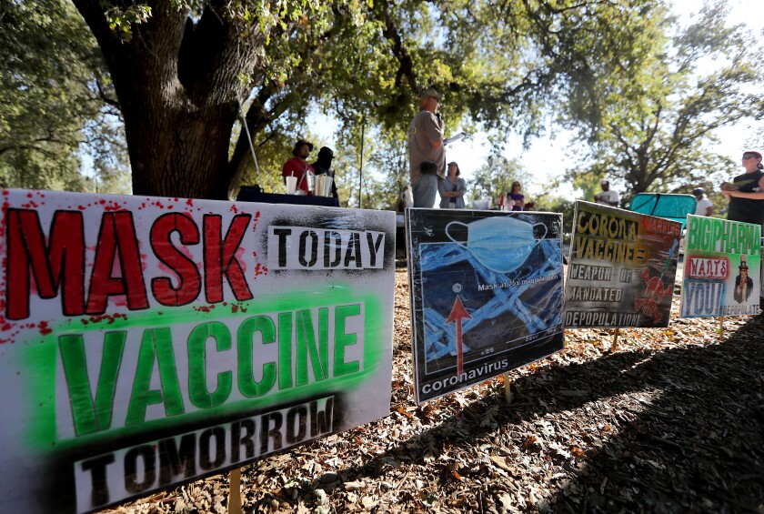 Signs against masks and vaccines are stuck in the ground