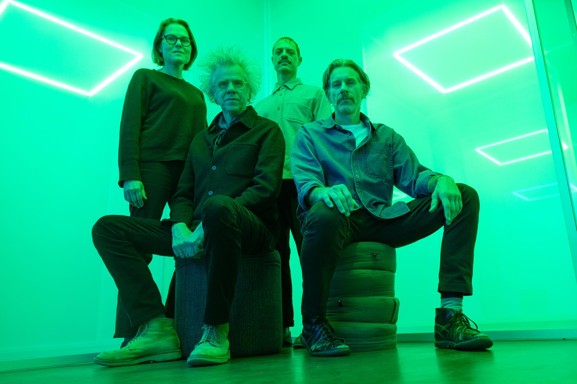 Four artists sit in front of meshes bathed in a greenish light.