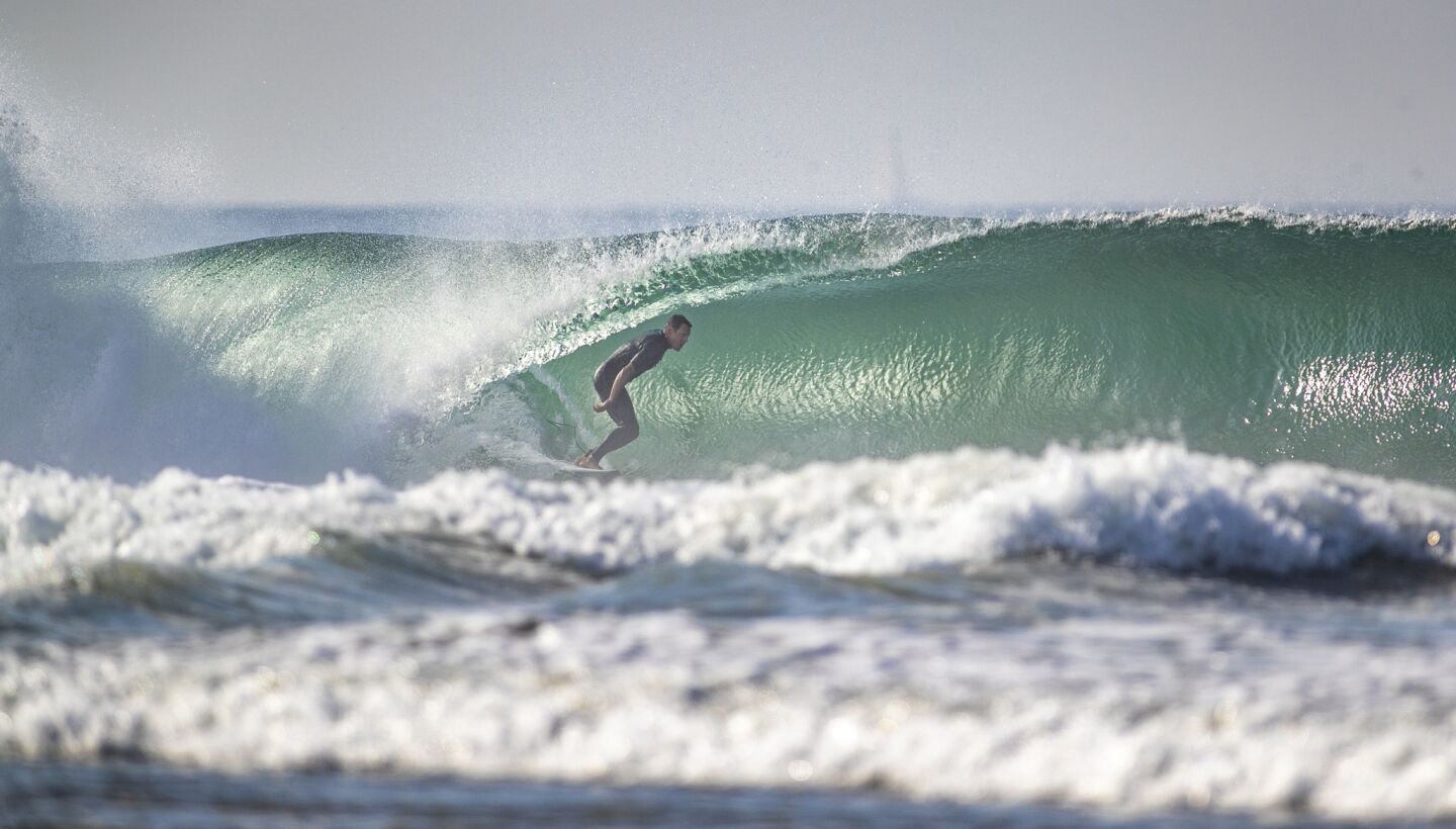 A surfer gets a tube ride amid high surf conditions at the Newport Point in Newport Beach.