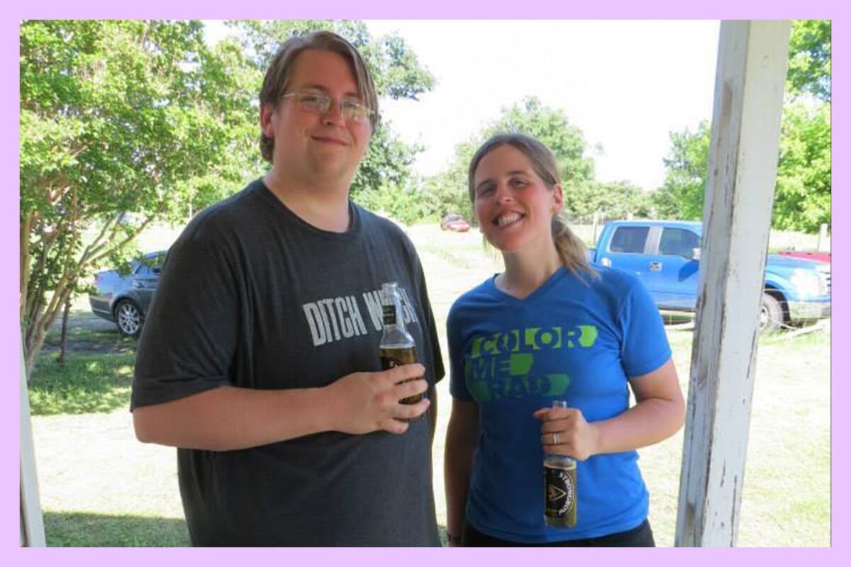 Two people holding beverages posing for the camera at an outdoors event