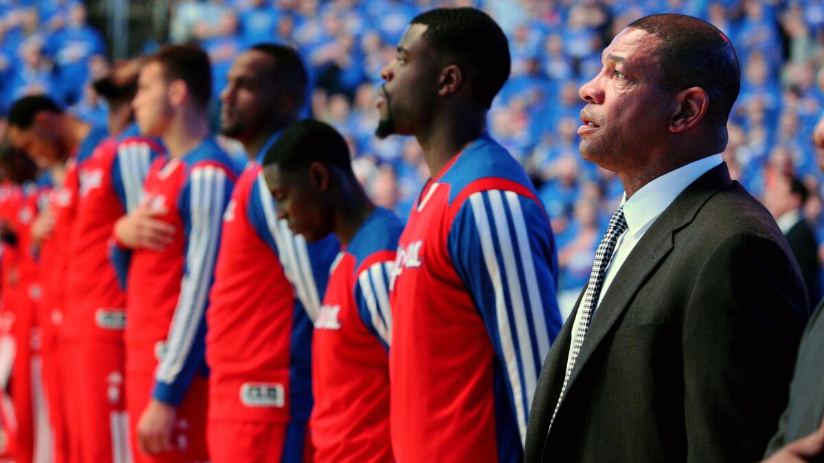 Clippers Coach Doc Rivers, right, listens to the singing of the national anthem while standing next to his players before the start of Game 1 of the Western Conference semifinals against the Oklahoma City Thunder on Monday. Rivers is trying to keep his players focused on beating the Thunder.