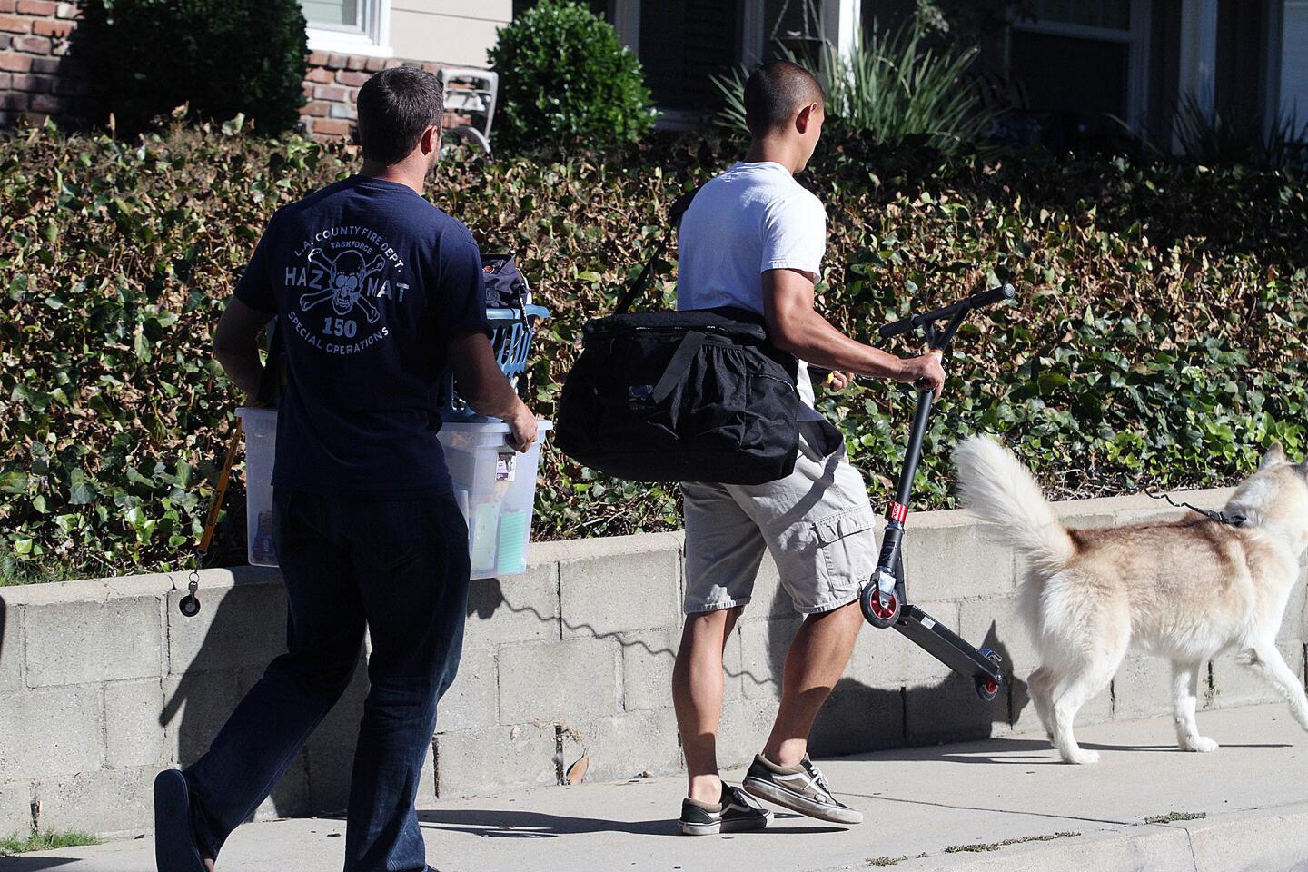 Two unknown men carry belongings and a dog from the scene of a murder-suicide on the 5000 block of Crown Avenue in La Cañada Flintridge on Monday, Sept. 7, 2015. On Sunday night, a 5-year veteran of the Los Angeles County Fire Department shot and killed his wife, a 2-year veteran of the Sheriff's Department. He then killed himself at a county Fire Department facility in Pacoima, according to officials.