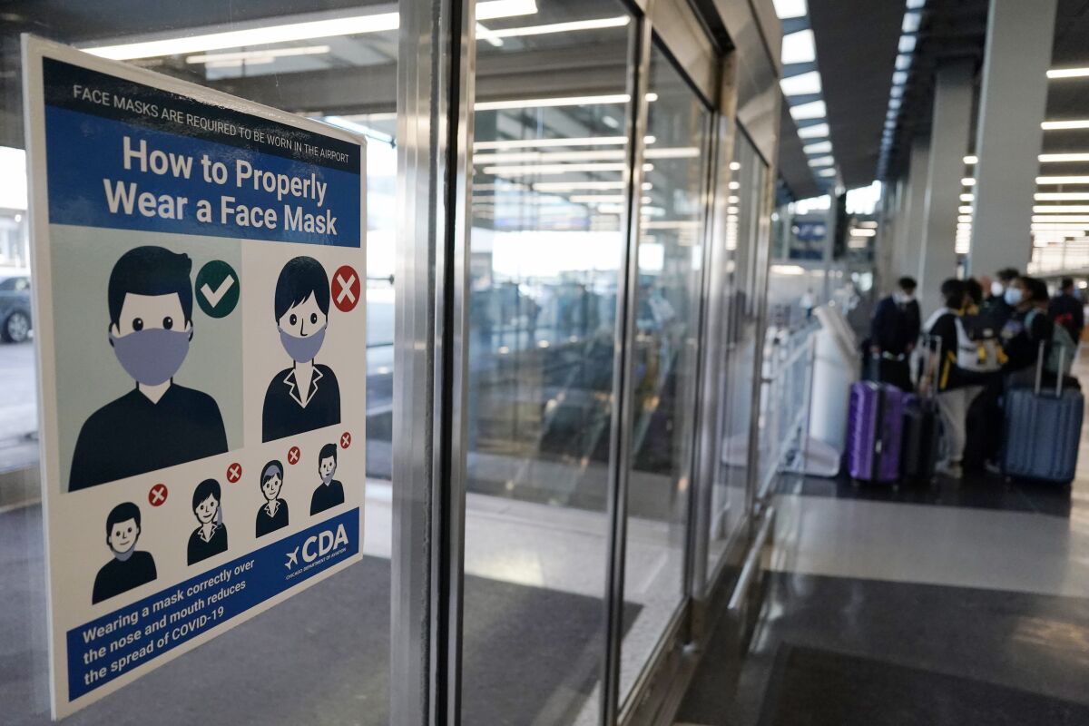 This July 2, 2021 photo shows a sign stating face coverings are required is displayed at O'Hare airport in Chicago. The nation’s top aviation regulator is asking local officials to consider filing criminal charges more often against people who act up during airline flights, Thursday, Aug. 5. Federal Aviation Administration chief Stephen Dickson says airline crews often ask police to meet their plane when it lands because of unruly passengers. (AP Photo/Nam Y. Huh)