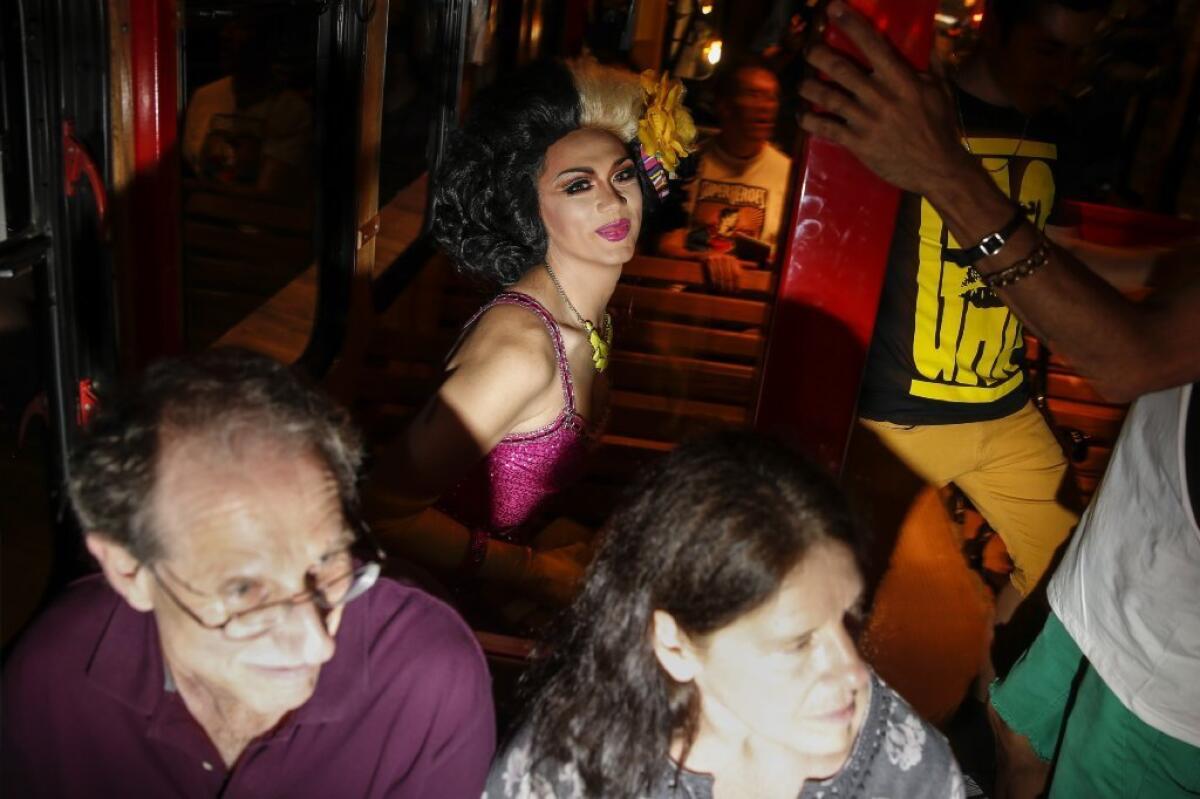 Drag queen Manila Luzon, a.k.a. Karl Westerberg, from TV's "RuPaul's Drag Race," sits behind Leonard Shapiro, 62, left, and his wife, Shari, 60, while on the inaugural ride of West Hollywood's PickUp line trolley along Santa Monica Boulevard in 2013.