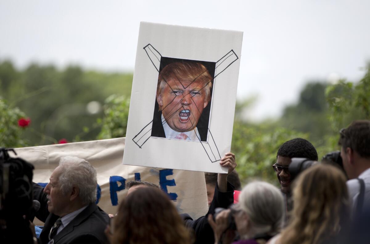 Protesters hold up a sign of Republican presidential candidate Donald Trump crossed out, near the new Trump hotel in Washington on July 9, in reaction to his portrayal of Mexican immigrants as criminals.