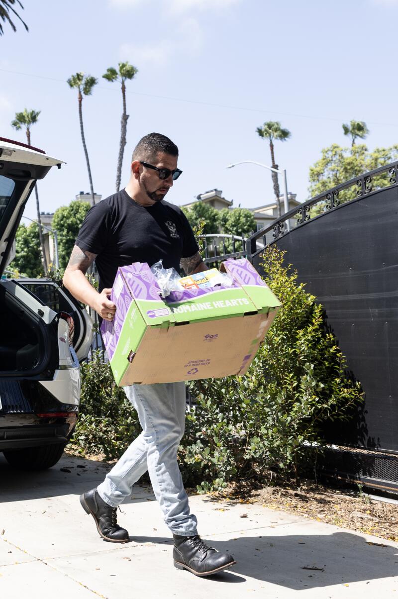El hombre mueve una caja de comida a través de un automóvil de una manera de clasificación