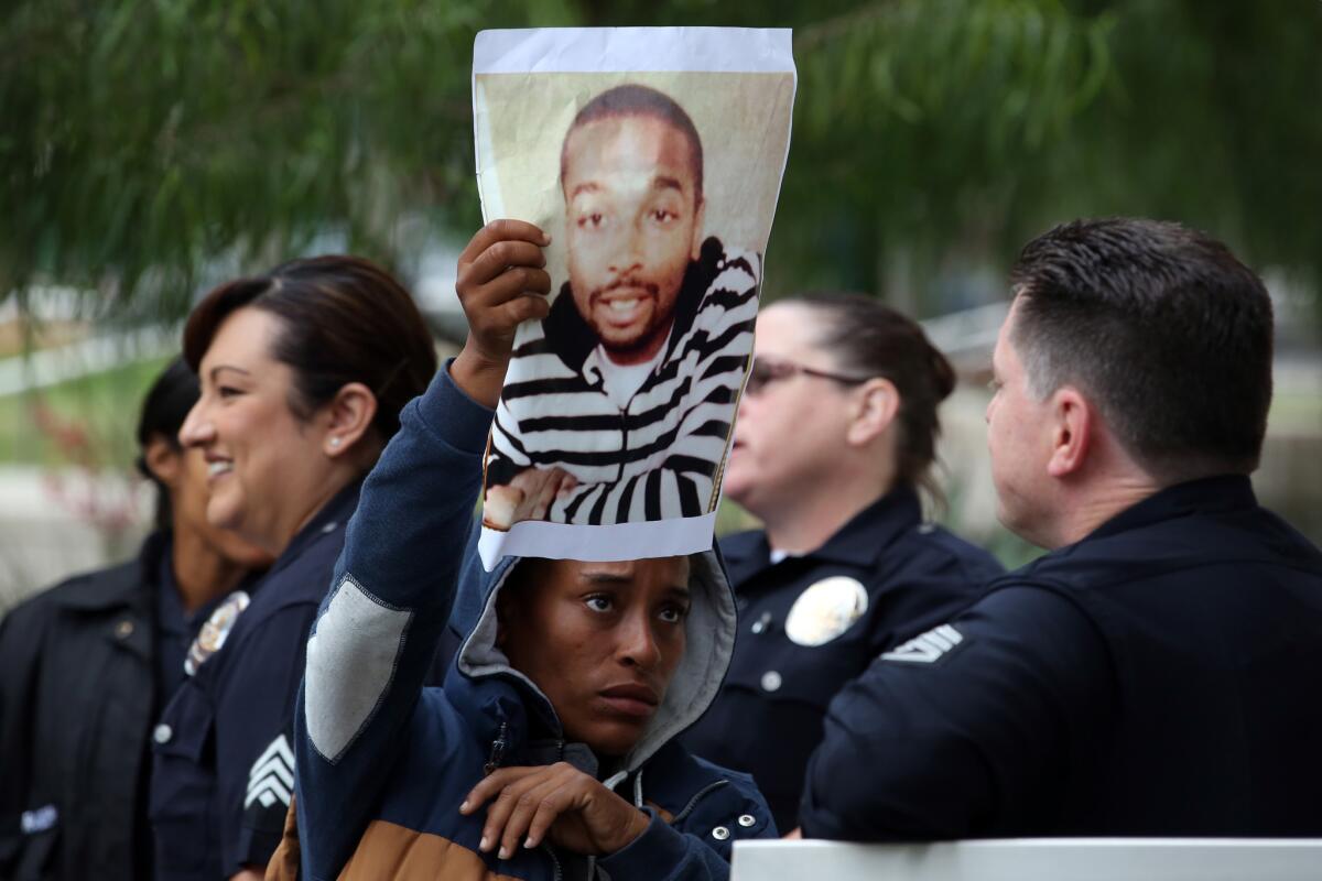 Jasmine Richards holds a picture of Ezell Ford outside LAPD headquarters Tuesday morning.