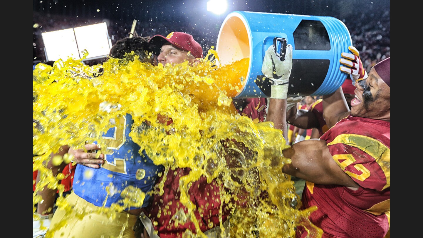 USC linebacker Uchenna Nowosu hits coach Clay Helton with a Gatorade bath following a 28-23 win over UCLA at the Coliseum.
