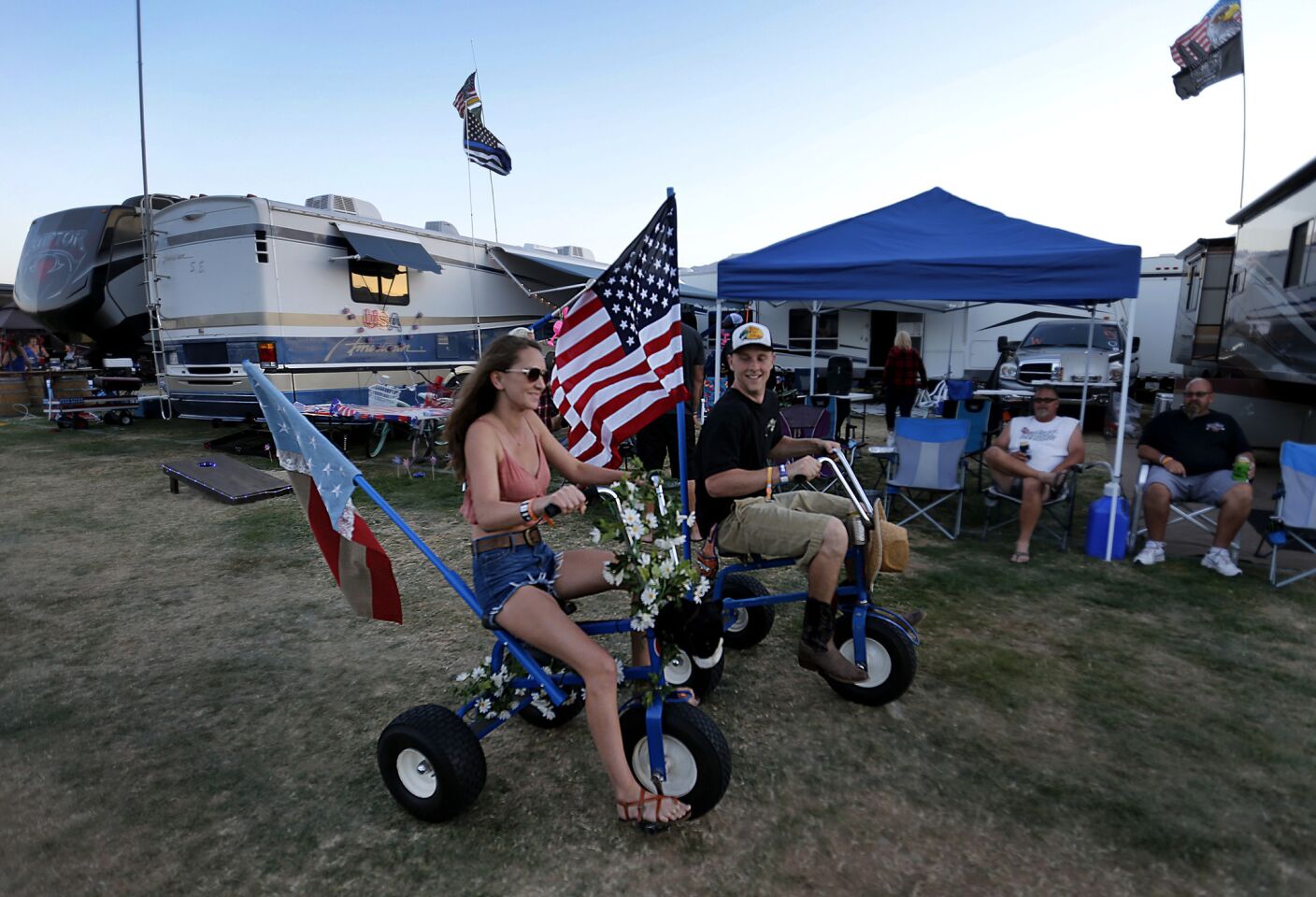 A couple cruise on three-wheel bikes with flags through the RV Resort for the 10th anniversary of the Stagecoach Country Music Festival.