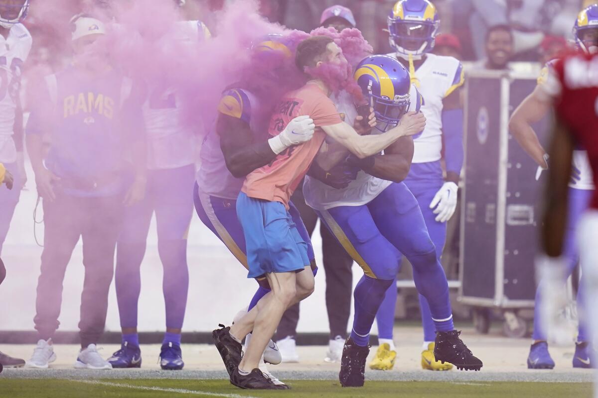 A protester is hit by Los Angeles Rams defensive end Takkarist McKinley, middle left, and linebacker Bobby Wagner during the first half of an NFL football game between the San Francisco 49ers and the Rams in Santa Clara, Calif., Monday, Oct. 3, 2022. (AP Photo/Godofredo A. Vásquez)