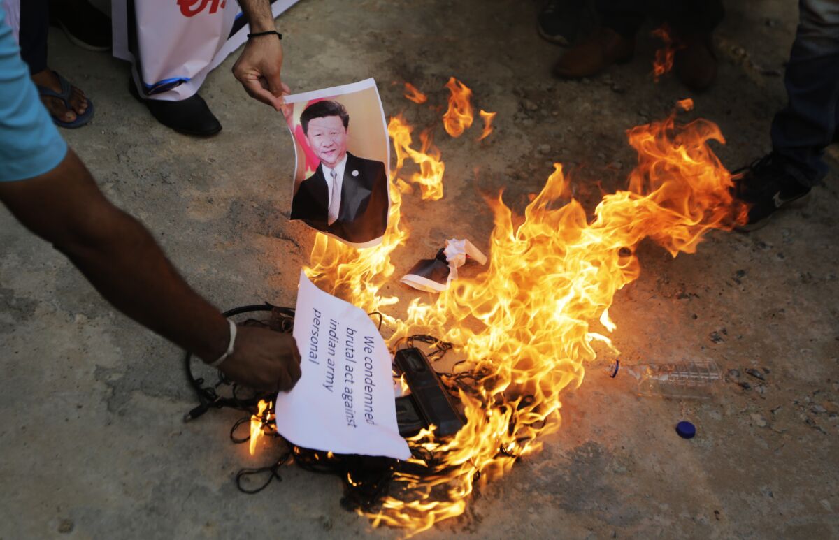 A man burns an image of Chinese President Xi Jinping during a protest in Ahmedabad, India, on June 16, 2020.