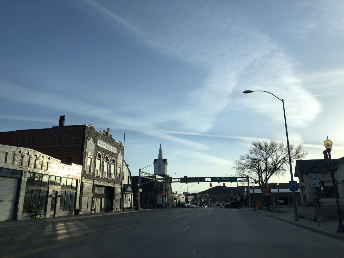 Low buildings line a main street in a small town at dusk.