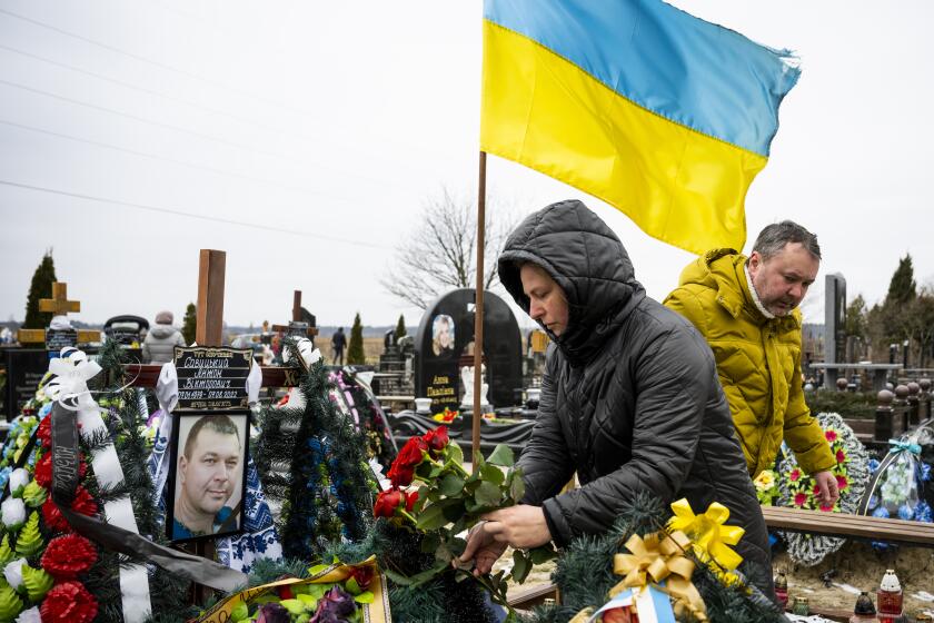 Mourners lay flowers at a grave on February 24, 2023 in Bucha, Ukraine. February 24th marked the one-year anniversary of Russia's full-scale invasion of Ukraine. Bucha was the scene of some of the worst atrocities so far recorded in the yearlong invasion.
