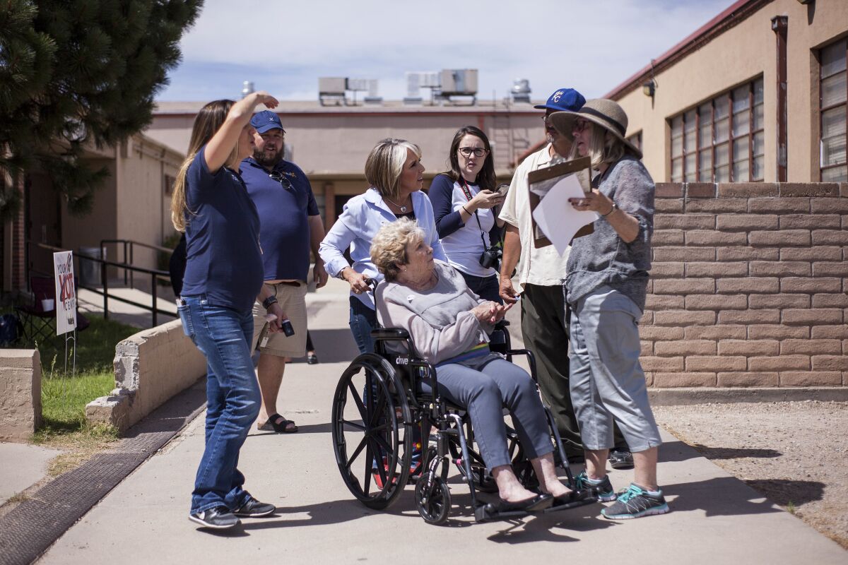 FILE - Michelle Lujan Grisham holds the wheelchair of her mother, Sonja Lujan, as they speak with voters after casting their ballots during the Democratic primary elections at Garfield Middle School in Albuquerque, N.M., on Tuesday, June 5, 2018. In a Monday, April 11, 2022 statement, the governor’s office said that Sonja Luhan, an advocate for children with disabilities, died on Sunday of natural causes. She was 82. (AP Photo/Juan Labreche,File)