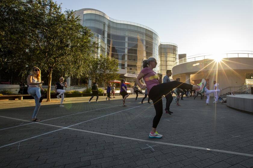 Kelsie Anderson, right, and others participate in a Brazilian capoeira class at Segerstrom Center's Argyros Plaza on Tuesday, August 10.