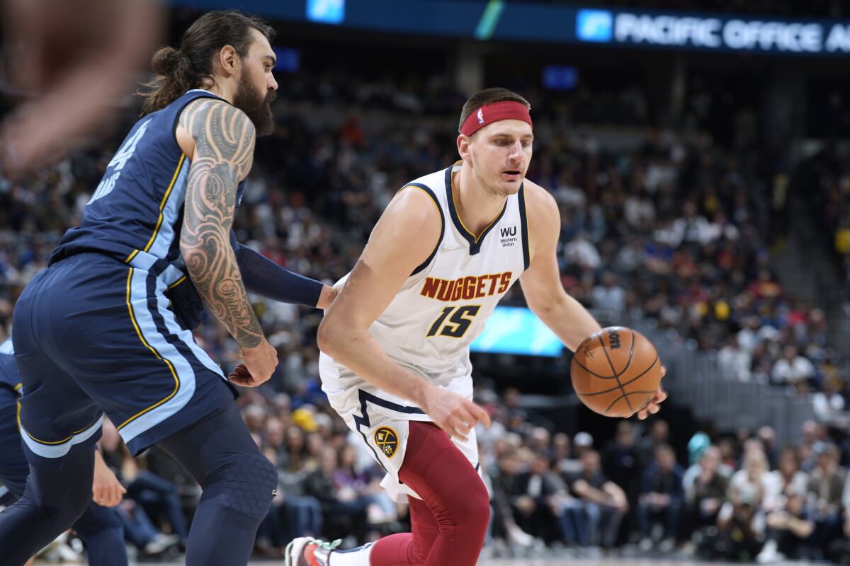 Denver Nuggets center Nikola Jokic, right, is defended by Memphis Grizzlies center Steven Adams during the first half of an NBA basketball game Thursday, April 7, 2022, in Denver. (AP Photo/David Zalubowski)