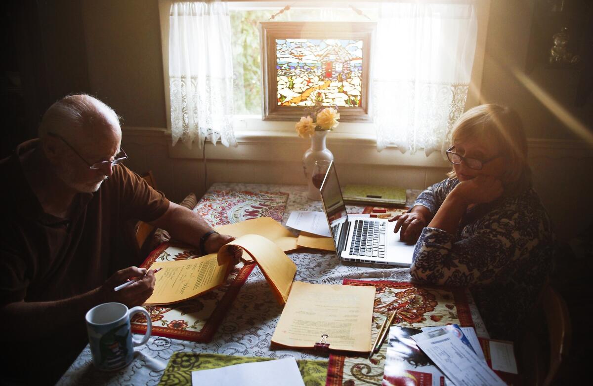 Bruce Hazelton and his ex-wife Janet Barker handle paperwork and pay bills at her house in Redondo Beach. They live in the small home with their daughter, their son-in-law and a grandchild.