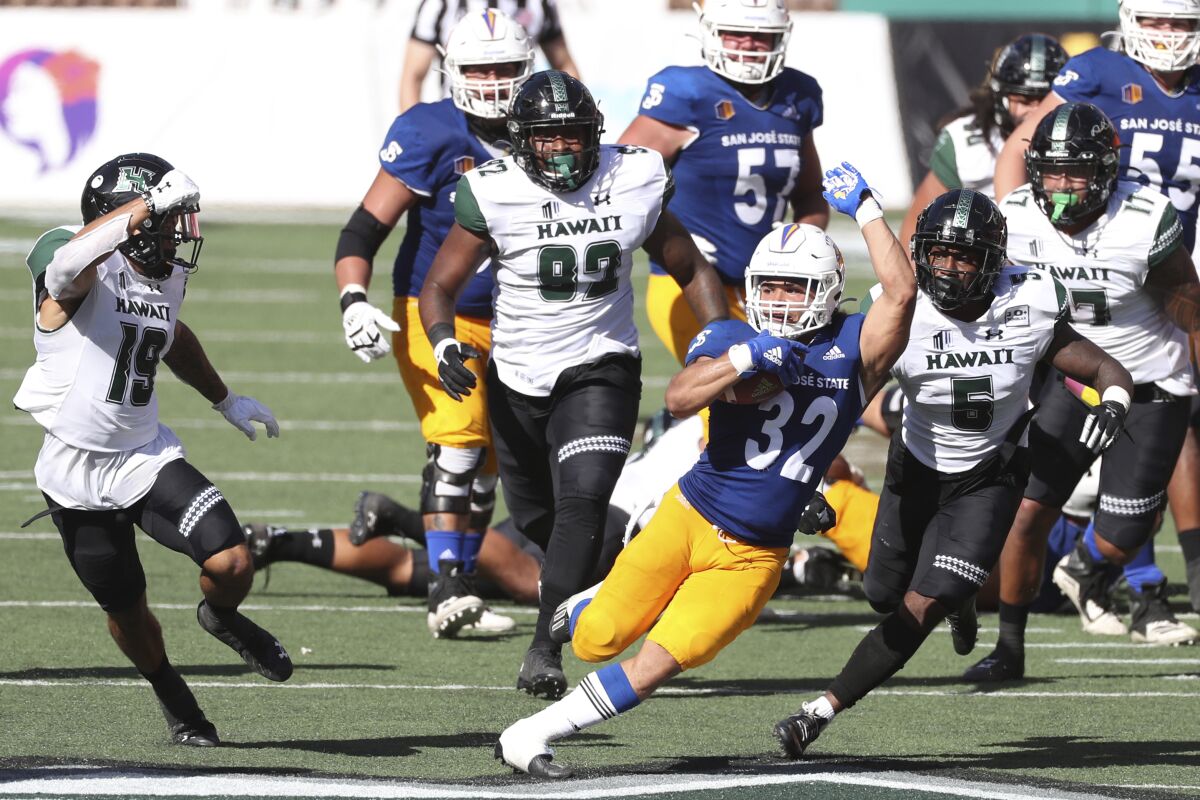 San Jose State running back Kairee Robinson (32) squeezes through the Hawaii defense in the first half of an NCAA college football game Saturday, Dec. 5, 2020, in Honolulu. (AP Photo/Marco Garcia)