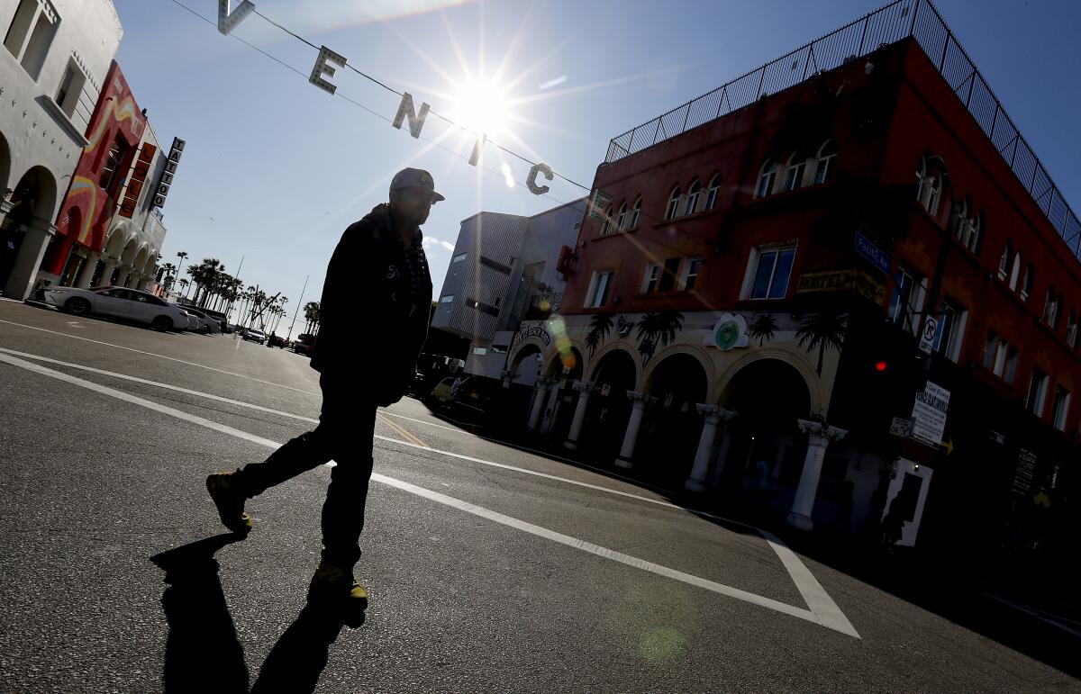 A pedestrian crosses the empty intersection of Windward and Pacific avenues in Venice. 